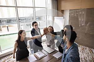 Cheerful multiethnic team of business colleagues giving group high five