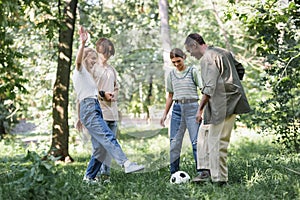 Cheerful multiethnic teenagers playing football in