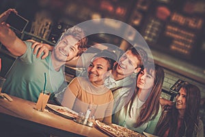 Cheerful multiracial friends having fun eating in pizzeria. photo