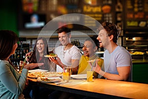 Cheerful multiracial friends having fun eating in pizzeria. photo