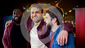 Cheerful multiracial friends hugging, celebrating bachelor party in bar, leisure