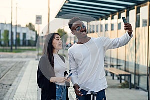 Cheerful multiracial male and female friends making selfie on smartphone with passports and tickets before joint trip.