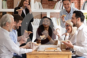 Cheerful multiracial office business people laugh share takeaway pizza together