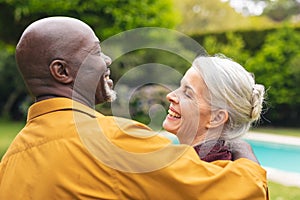 Cheerful multiracial senior couple spending leisure time together in backyard
