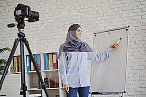 Cheerful Muslim business coach showing something on a whiteboard