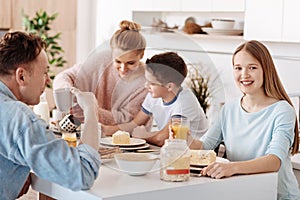 Cheerful nice girl having breakfast with her friendly family
