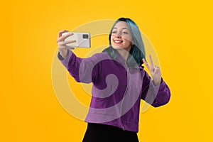 Cheerful nice young girl with blue hair taking selfie