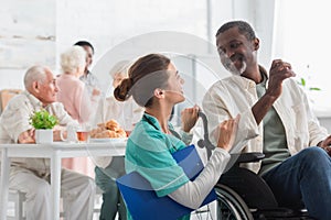 Cheerful nurse with clipboard talking with photo