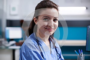 Cheerful nurse in office, wearing scrubs