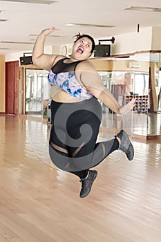 Cheerful obese woman jumps in the fitness center