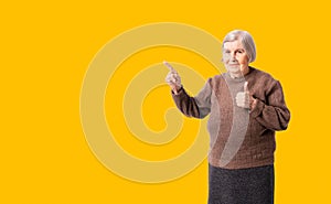 Cheerful octogenarian woman wearing brown sweater showing on empty place for copy space.
