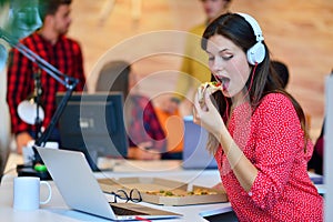 Cheerful office girl enjoying pizza at lunchtime photo