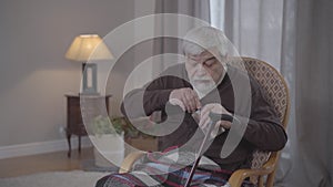 Cheerful old Caucasian man drinking alcohol from flask and hiding it away. Disobedient resident of nursing home looking