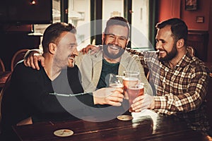 Cheerful old friends having fun and drinking draft beer in pub.