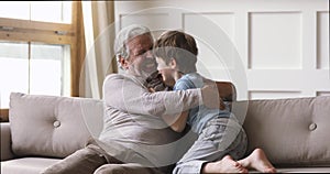 Cheerful old grandpa and cute grandson laughing playing at home