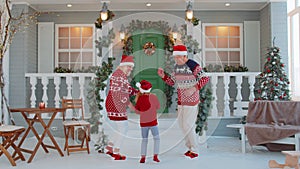 Cheerful old grandparents with granddaughter child kid dancing around decorated Christmas house tree