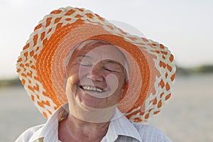 Cheerful old lady in a hat laughing happily.