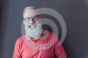 Cheerful old male in glasses is standing with smile