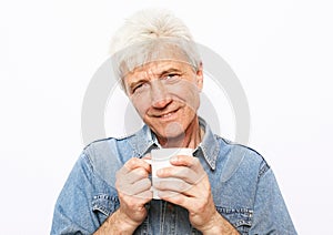 cheerful old man holding a mug of coffee and smiling on white background