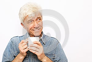 cheerful old man holding a mug of coffee and smiling on white background