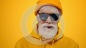 Cheerful old man raising hands indoors. Joyful guy posing to camera in studio.