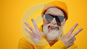 Cheerful old man raising hands indoors. Joyful guy posing to camera in studio.