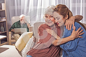 Cheerful old mother hugging smiling woman