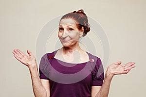 A cheerful old woman laughs and rejoices. Portrait over grey background.