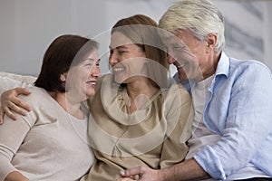 Cheerful older couple of parents and daughter meeting at home