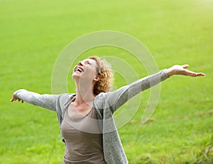 Cheerful older woman smiling with arms outstretched