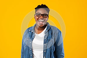 Cheerful Oversized Black Lady Wearing Eyeglasses Posing On Yellow Background photo