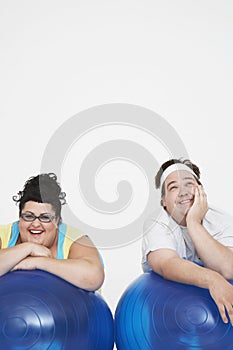 Cheerful Overweight Couple Resting On Exercise Balls