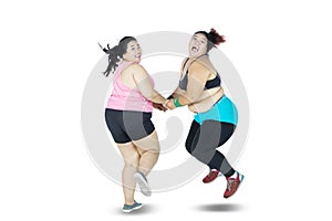 Cheerful overweight women jumping in studio