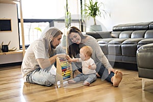 Cheerful parent playing with his baby girl on floor at living room