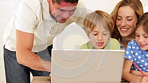 Cheerful parents and children doing arts and crafts together with laptop