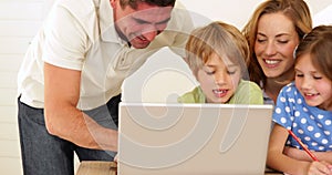 Cheerful parents and children doing arts and crafts together with laptop