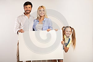 Cheerful Parents And Daughter Holding Blank Board, White Background