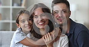 Cheerful parents and little daughter kid looking at camera