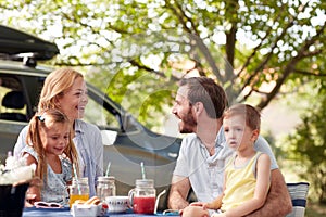 Cheerful parents looking each other, smiling, laughing, with their kids in their laps