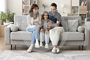 Cheerful parents and sweet daughter taking funny home family selfie