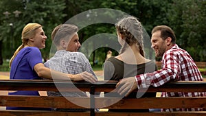 Cheerful parents and their teenage children planning weekend on bench in park