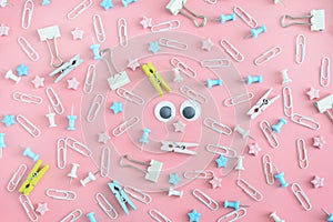 Cheerful pattern. Stationery chaotically scattered on a pale pink background. Doll eyes in the center of the confusion