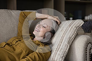 Cheerful peaceful elderly woman wearing headphones listening to music