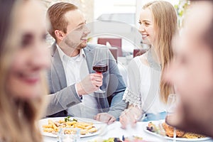 Cheerful people enjoying drink and food in Italian restaurant