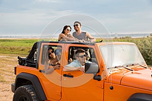 Cheerful people having fun be travelling together by a car