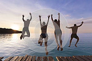 Cheerful people having fun jumping in water from pier