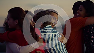 Cheerful people hugging at evening party. Buddies greeting each other outdoors.