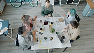 Cheerful people multiethnic group discussing project then clapping hands and doing high-five in office