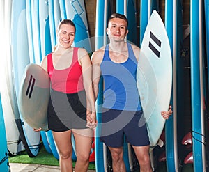 Cheerful people standing with surfboards