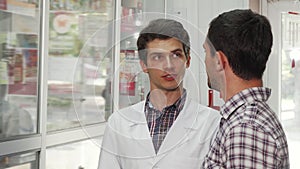 Cheerful pharmacist helping male customer choosing products to buy